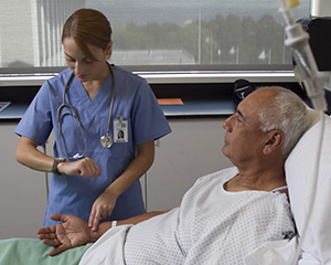 Health care provider checking man's pulse at hospital bed.