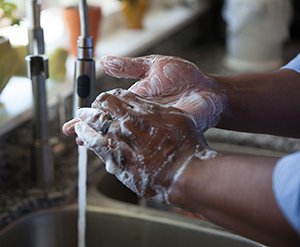 Closeup of handwashing in sink with soap and running water.