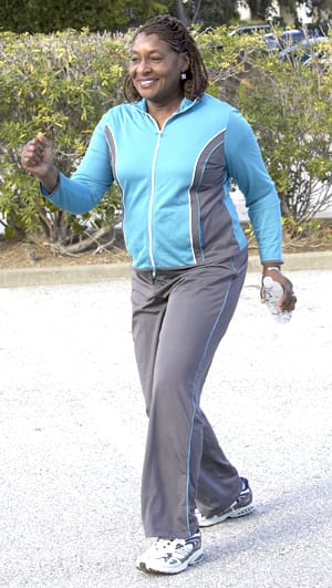 Woman in comfortable clothes walking. outside carrying bottle of water.