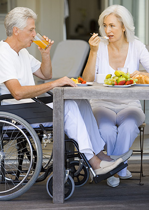 Woman and man in wheelchair eating breakfast.