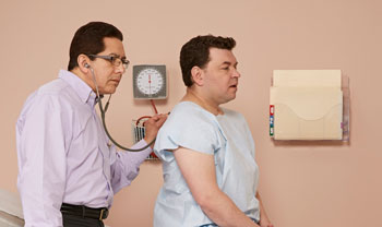 Health care provider using stethoscope to listen to patient's breathing.