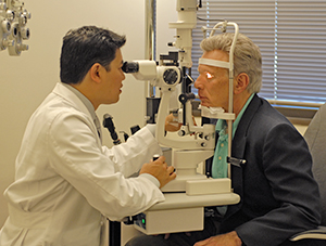 Health care provider examining man's eyes with slit lamp.