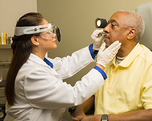 Healthcare provider examining man’s nose.