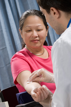 Healthcare provider preparing to draw blood from woman's arm.