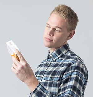 Man reading box of over-the-counter medicine.