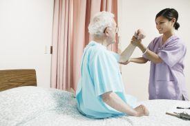 Therapist manipulating the arm of an older man who is in the hospital