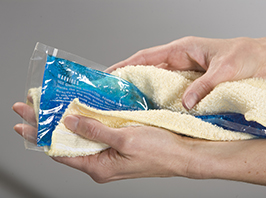 Closeup of hands wrapping ice pack in towel.
