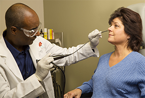 Healthcare provider preparing to insert endoscope into woman’s nose.