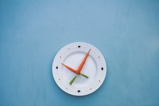 Dinner plate with carrots and celery placed as clock hands