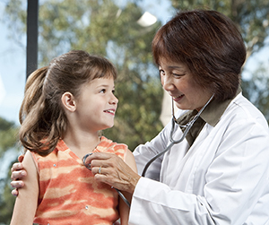 Doctor listening to girl's chest with stethoscope.