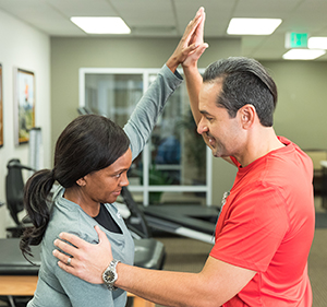 Physical therapist working with woman on arm stretches.