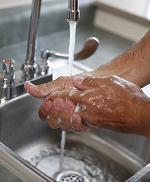 Closeup of man washing hands in sink.