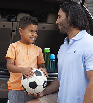 Man talking to boy with soccer ball.