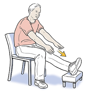 Man sitting with foot on stool doing leg stretch exercise.