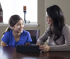 Woman and teen girl looking at electronic tablet.