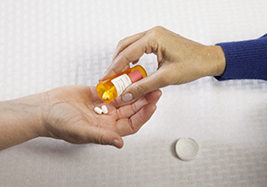 Woman's hand putting pills in another woman's hand