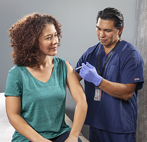 Health care provider giving woman injection in arm.