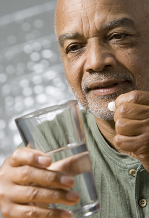 Man taking pill with glass of water.