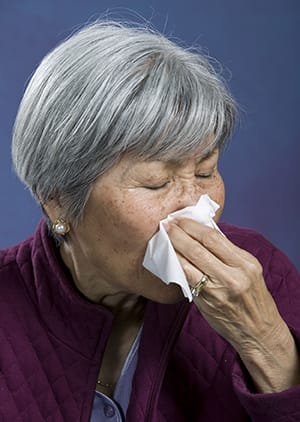 Person holding tissue to nose.