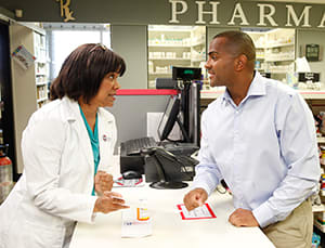 Pharmacist talking to person at pharmacy counter.