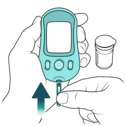 One hand holding glucometer and other hand inserting test strip into glucometer, with test strip bottle in background.