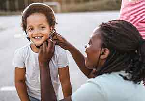 Woman putting bike helmet on preschooler girl.