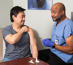 Health care provider giving man vaccine injection.